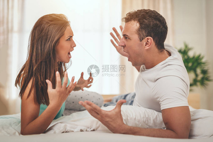 愤怒的年轻夫妇在床上争吵他们图片