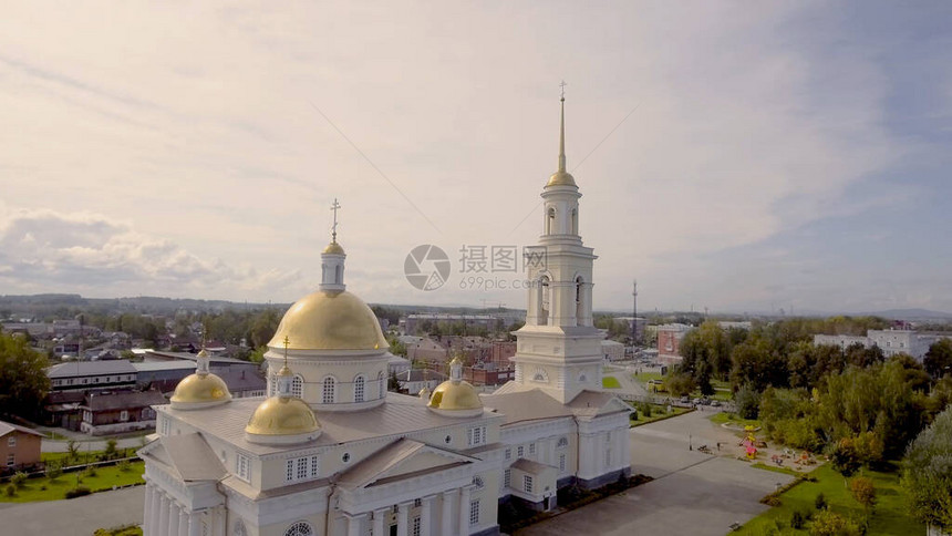 夏季美丽的寺庙与金色圆顶和钟楼的顶视图影视素材带有钟楼的光寺金色圆顶在夏日小镇的背图片