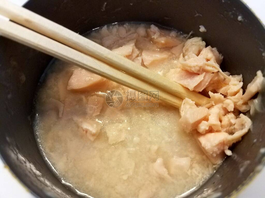 用筷子在肉汤中打开罐装白肉鸡罐头图片