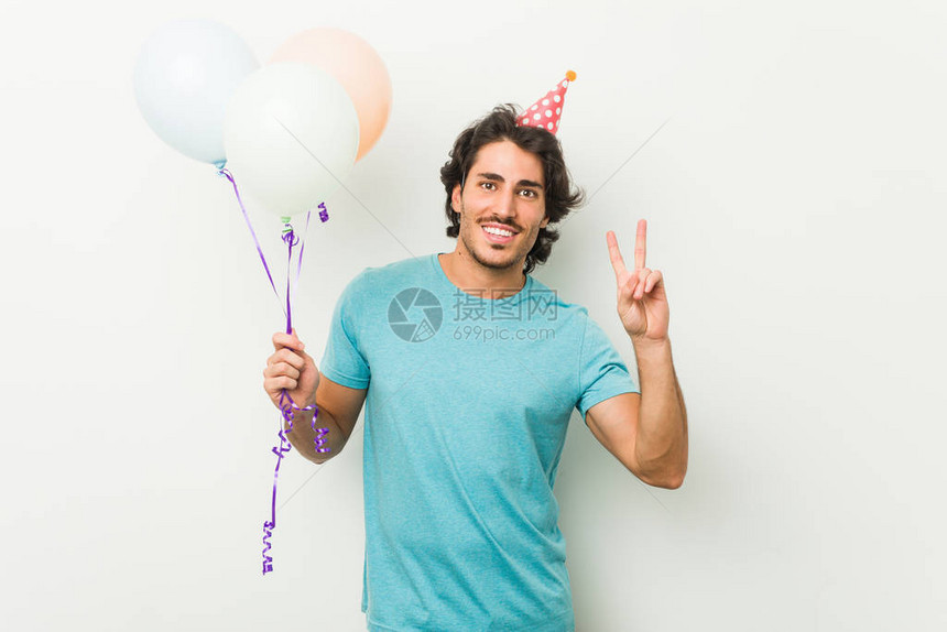 年轻人庆祝一个党持有气球展示胜利标志和微图片