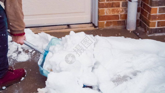 年轻人从车道上铲雪图片