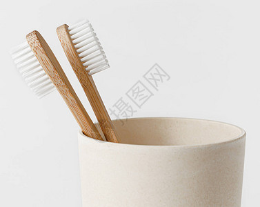 白色背景的生态杯中的竹子牙刷复制空间关闭背景图片