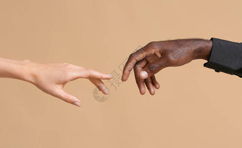 高加索女和非裔美洲男双手在肤色背景方面相互接触图片