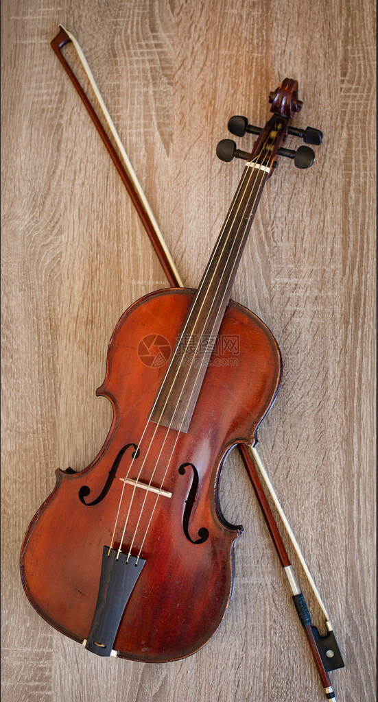 木制背景上的小提琴小提琴和弓图片