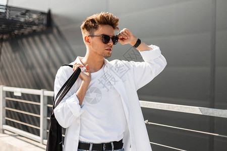 时尚发型的年轻时髦男人拉直了黑色太阳镜图片