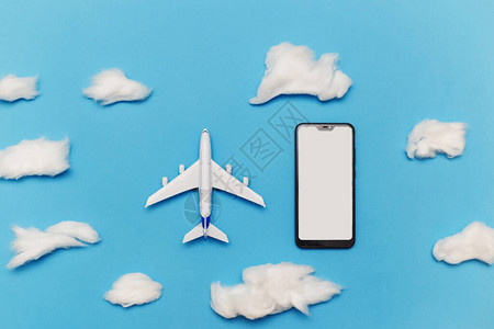 玩具飞机和智能手机与蓝色背景上的空白屏幕平躺网上订票旅图片