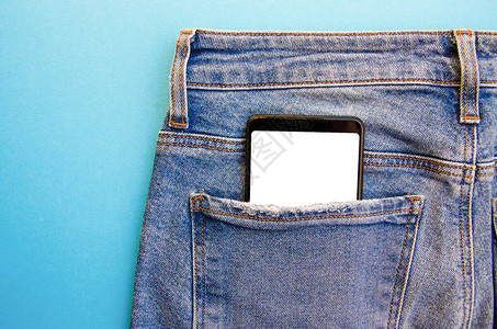 牛仔裤口袋里的白屏智能手机文本的智能手机地方蓝色背景上口袋里的智能手图片