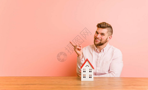 年轻的caucasian男子坐在一栋房子的图标上图片