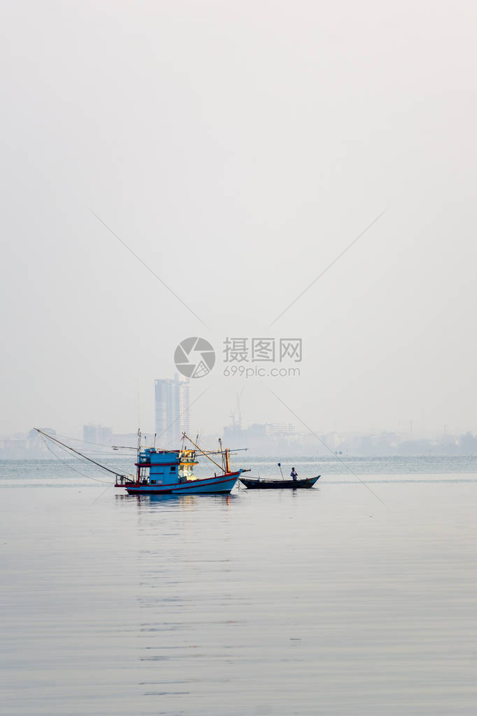 一艘小渔船停泊在海岸附近钓鱼时停下来图片