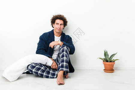 身着睡衣的成熟男子坐在房子地板上感到困惑图片