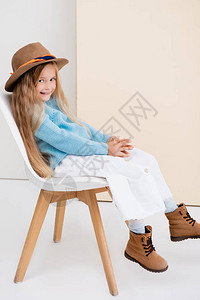 穿着棕色帽子和靴子白裙子和蓝毛衣的时装金发美女图片