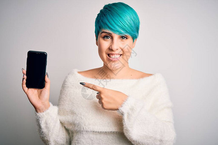 蓝色时装发型的年轻女子拿着智能手机在屏幕上非常快乐地用图片