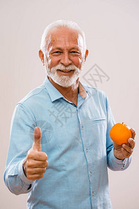 拿着橙子微笑的开朗老人的肖像图片
