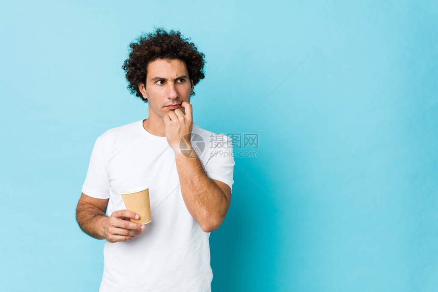 年轻caucasian卷毛男拿着外送咖啡放松了思考的东西看图片