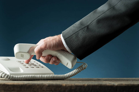 一名商人手持白色陆上电话的电话传呼机拨号背景图片