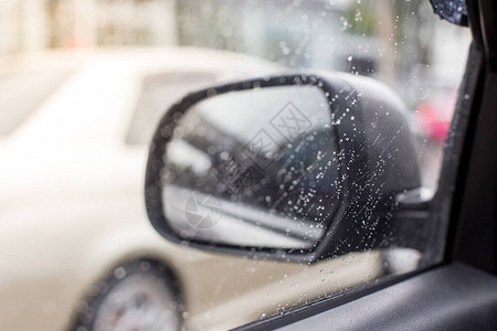 汽车侧镜上的雨滴有选择地聚焦于模糊背图片