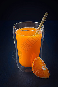 深蓝色桌上的新鲜橘子汁背景图片