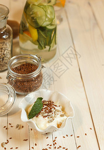 轻木桌上的白瓷碗里放着亚麻和葵花籽的酸奶图片