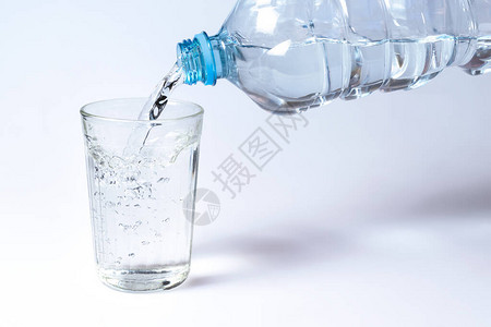 从塑料瓶中倒入面玻璃的水在白色背图片