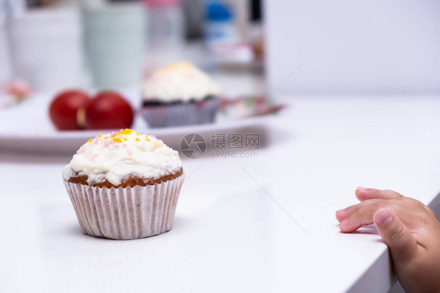 孩子们的手伸去拿蛋糕蛋糕白色桌子上的杯形蛋图片