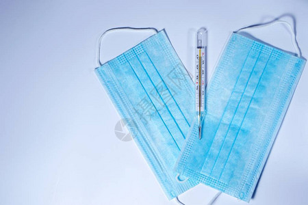 在白色背景上隔离的蓝色医疗面具和汞温度计保护图片