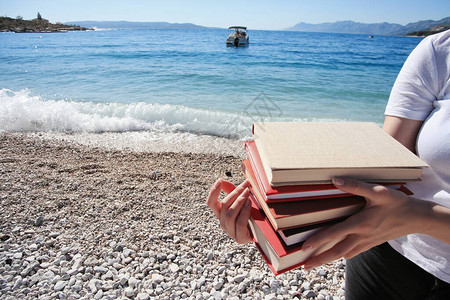 有个年轻美女拿着书在海边图片