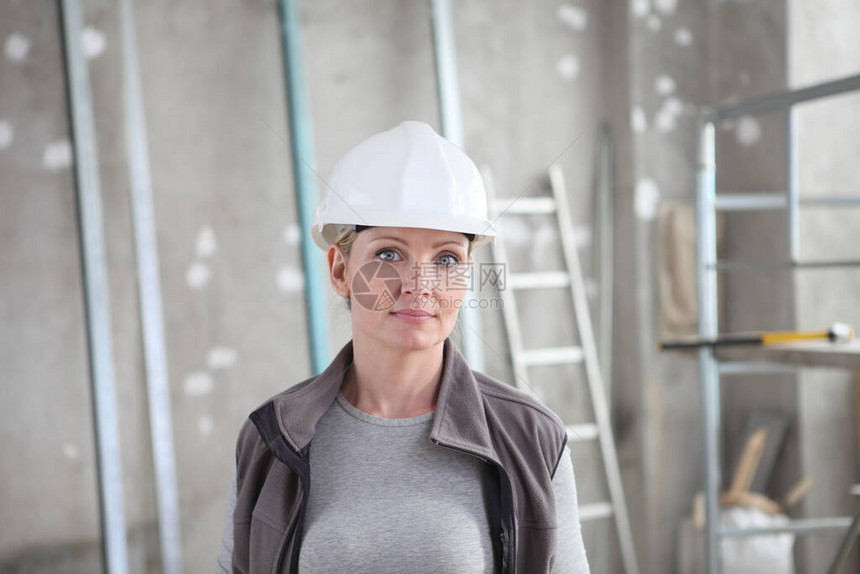 内地建筑背景脚手架和梯子上身着白头盔的建筑工妇女建筑图片