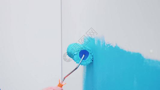 用蓝色油漆涂在墙上的滚刷在装修和改善的同时进行公寓装修和房屋建设背景图片