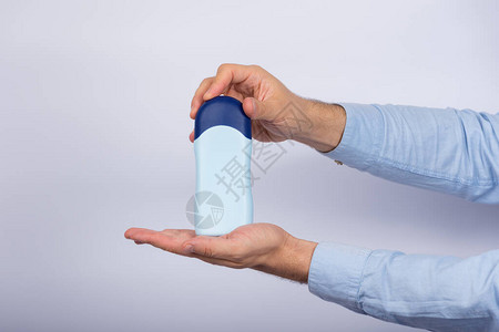 男人在白色背景上拿着一瓶洗发水或调味剂复图片