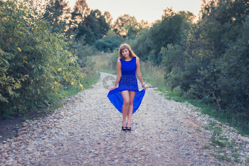 穿着蓝裙子的漂亮女孩假扮在自然图片