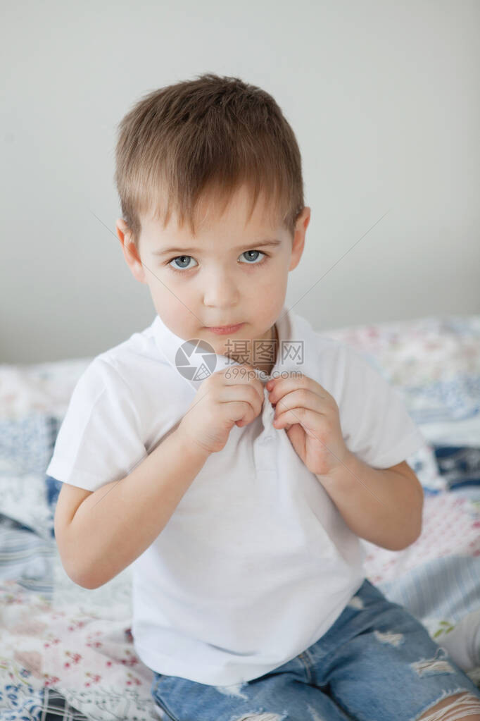穿白色T恤和蓝色牛仔裤的年轻男孩在卧室图片