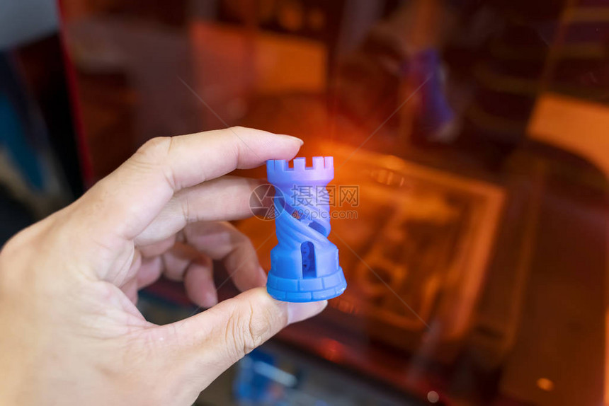 印在3d打印机特端上的印有塑料象棋的手图片