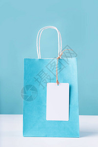 白色桌子上有空白色标签的蓝色购物袋图片