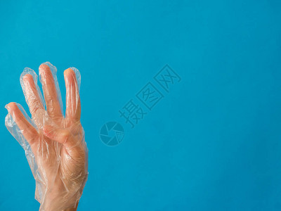 手持塑料手套四只手指在蓝色背景和复图片