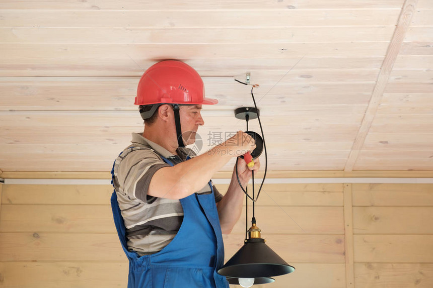 电气工程师在新的木房子里安装吸顶灯在房间里安装电灯图片