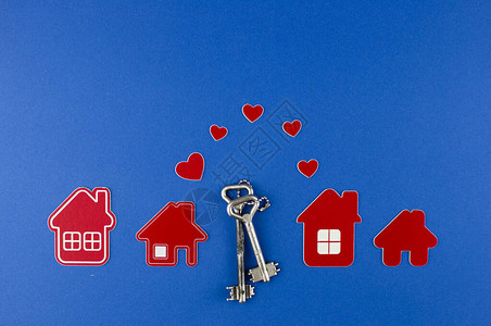 蓝色背景上的钥匙和房子形状的钥匙链排列图片