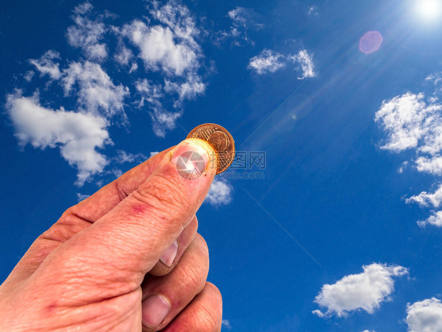 手拿着硬币在蓝天的背景下上帝的礼物祷告请求帮助他们要钱给予者的手阳光欧元钱图像在背景中图片