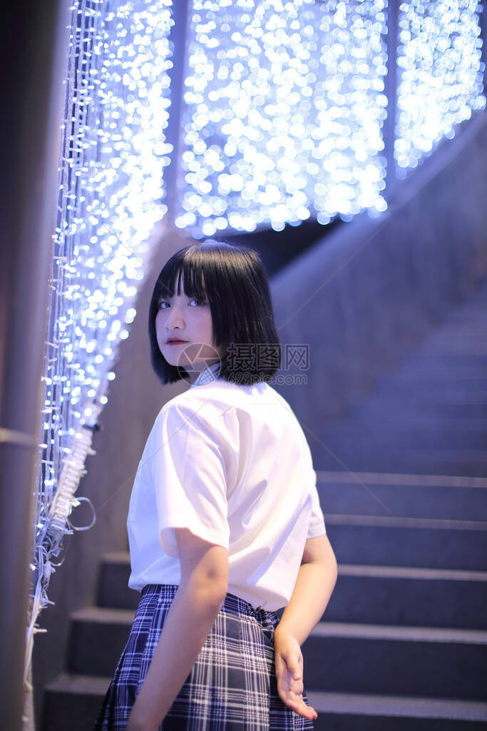 穿着日本女学生服装在城市夜里与bokeh相望的图片