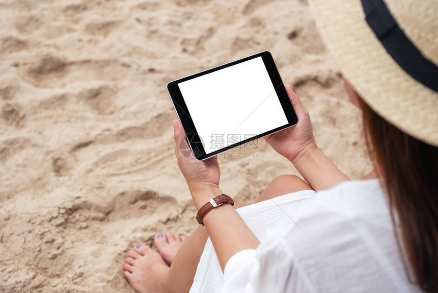 一个女人坐在沙滩椅上时拿着一张黑色平板电脑图片