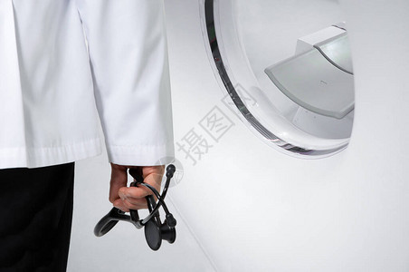一位医生拿着黑色听诊器站在CT扫描仪前高清图片