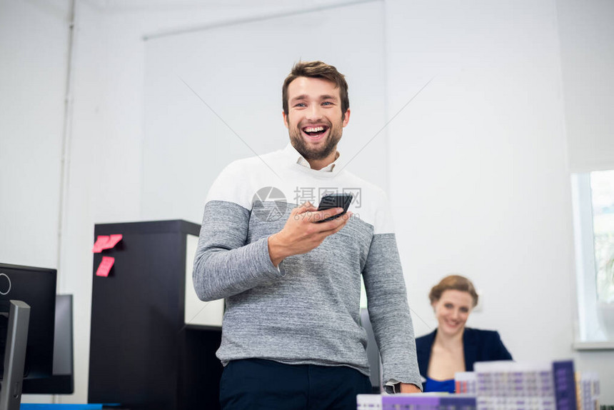 一个长着胡子的年轻男子在办公室里笑手里拿着一图片