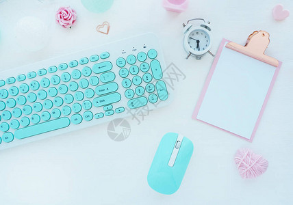 薄荷白鼠标和键盘粉色剪贴板回形针蜡烛闹钟白色桌子上的粉色纸花图片