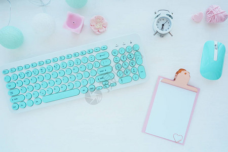 薄荷白电脑鼠标和键盘粉色剪贴板回形针蜡烛闹钟白色桌子上的粉色纸花平面图片