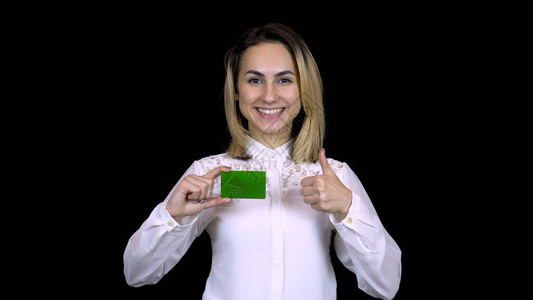 身着白衬衫的年轻女商人手里拿着一张银行卡背景图片