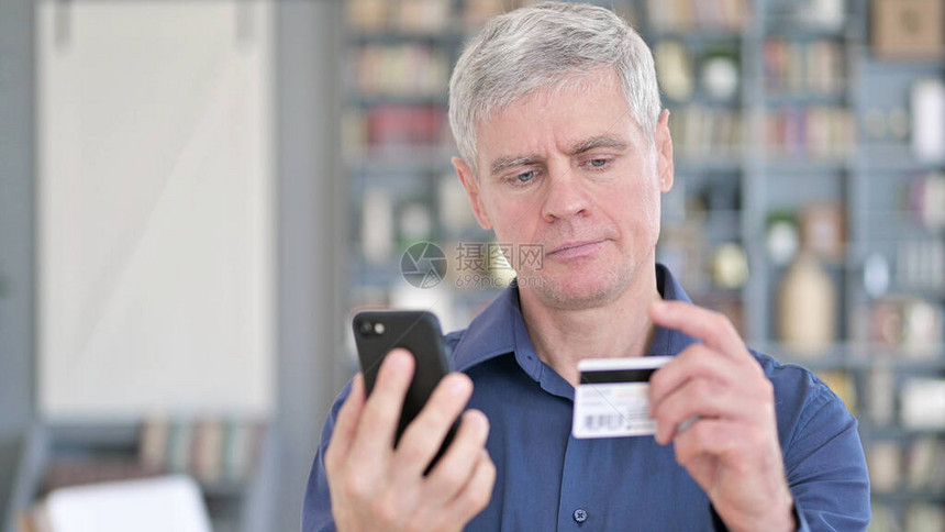 使用智能手机信用卡成功中年男子的图片