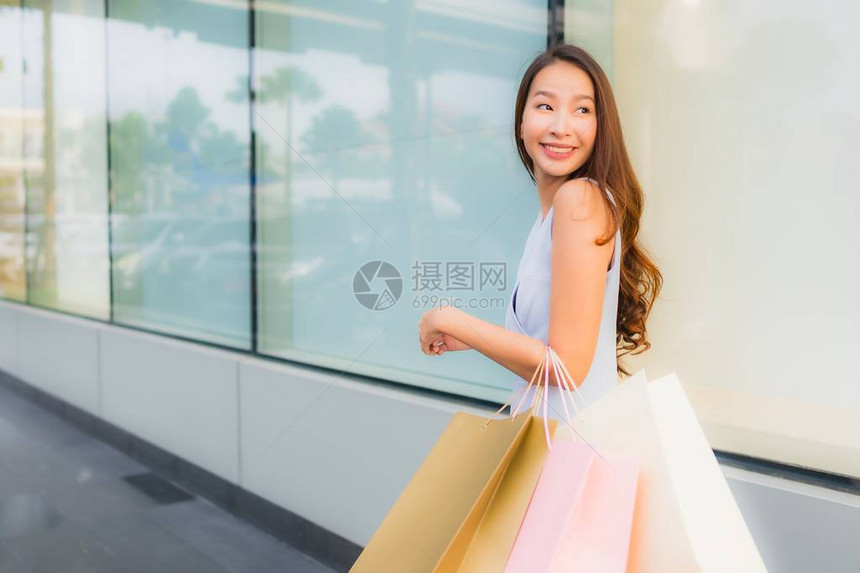 美貌丽的年轻亚洲妇女快乐笑着与百货商场购物袋一起微笑图片