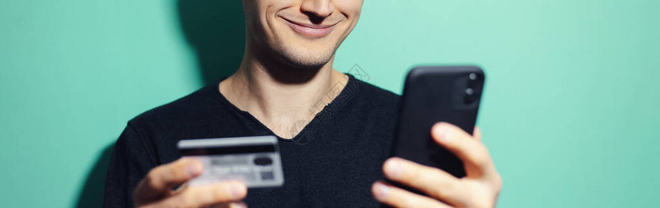 带着智能手机和信用卡的笑脸家伙近乎全景的肖像以青色图片