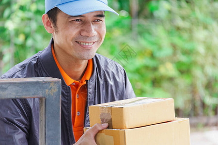 坐在家外等待客户接收产品时微笑着戴蓝帽子的亚洲图片