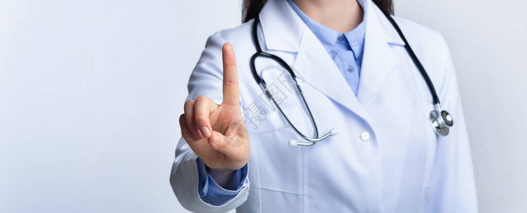 无法辨认的医生在站灰色工作室背景的医疗触摸屏上按下隐形按钮图片