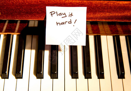 古典钢琴键盘上的手写字条告诉钢琴家要硬弹一下它图片